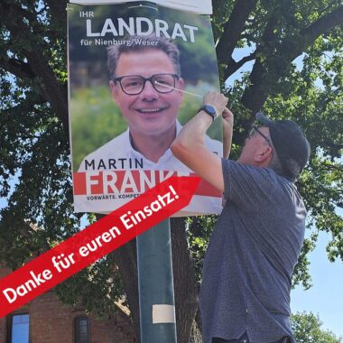Ralf Schulte hängt in Münchehagen ein Wahlplakat von Martin Franke auf.