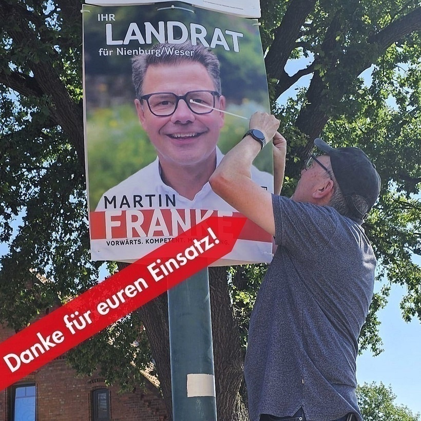 Ralf Schulte hängt in Münchehagen ein Wahlplakat von Martin Franke auf.